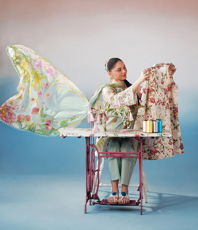 A woman sits at a vintage sewing machine table, holding up a floral-patterned garment while a matching sheer floral fabric billows from an ironing board setup. The scene is styled with pastel tones and multiple color-coded spools of thread on a blue gradient studio background.